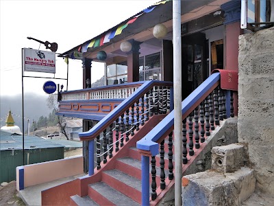 An exterior photo of The Hungy Yak restaurant, showing signage and a facade and staircase painted with red and blue.